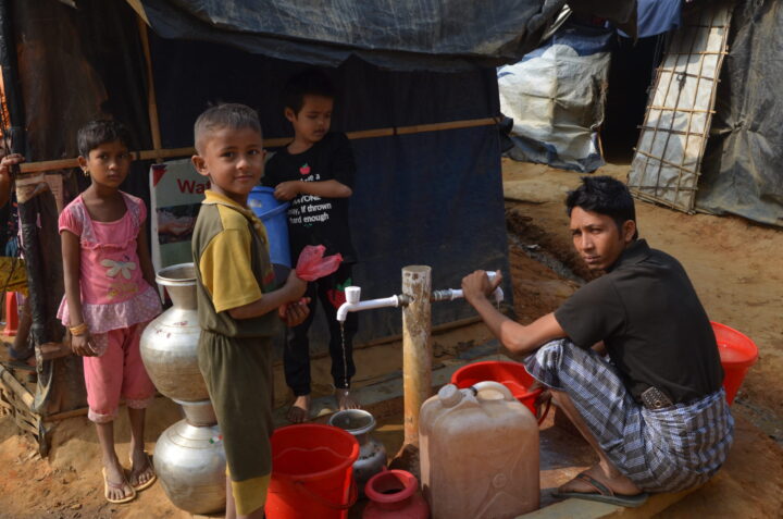An adult and two children using a well
